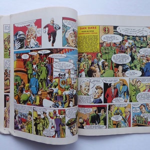 May include: A comic book open to a page featuring a colourful illustration of a group of people in military uniforms. The text on the page reads "Dan Dare, Pilot of the Future, Course in Space".