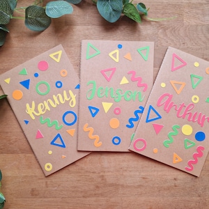 Cuadernos personalizados con formas y colores del arcoíris o pastel. Perfectos para regalos de fiestas, regalos para el aula o para rellenar medias. Tamaño A5, 14 x 21 cm. En blanco.