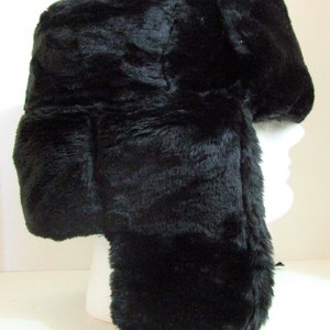 Puede incluir: Un gorro ushanka de piel sint&eacute;tica negra con una larga solapa para las orejas que se ata bajo la barbilla.