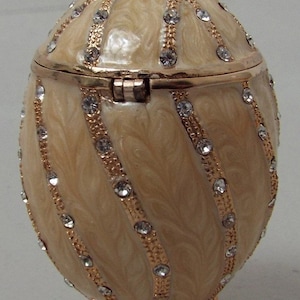 Russian Replica Beige Stone Faberge egg type, designed with spiral golden bands that have many gemstones embedded.