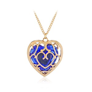 May include: A gold heart-shaped pendant necklace with a blue crystal inside. The pendant has a delicate, intricate design.