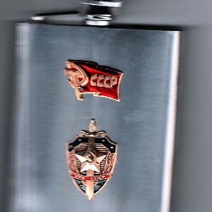 May include: A silver flask with a red and gold USSR flag pin and a gold shield with a star and sword pin.