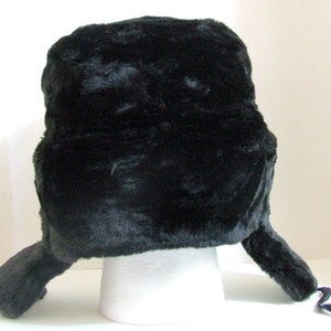 Puede incluir: Un gorro trapero de piel sint&eacute;tica negra con orejeras y una correa para la barbilla.