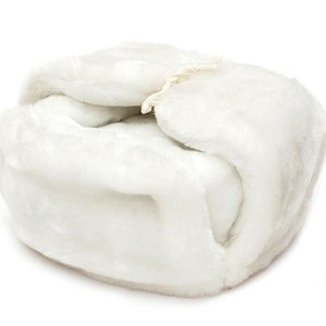 Op de afbeelding: Een witte nep bontmuts met een simpel ontwerp. De muts is dubbelgevouwen en de bont is zacht en pluche.