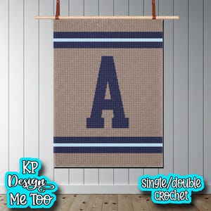 May include: A rectangular crochet wall hanging featuring a large, dark navy blue letter A centered on a tan background. The design includes horizontal stripes in dark navy blue and light blue at the top and bottom. The piece hangs from a wooden rod.