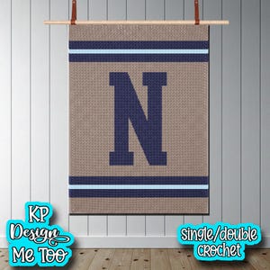 May include: A rectangular crochet wall hanging featuring a large dark blue letter N centered on a tan background. The design includes horizontal stripes of dark blue and light blue at the top and bottom, suspended from a wooden rod with leather straps.