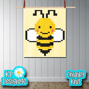 Puede incluir: Un diseño de abeja pixelada amarilla y negra sobre un fondo amarillo claro. La abeja tiene alas blancas y mejillas rosas. La obra de arte se muestra en una varilla de madera con correas de cuero. Las palabras "KP DesignMe" y "Chunky Knit" están en la imagen.