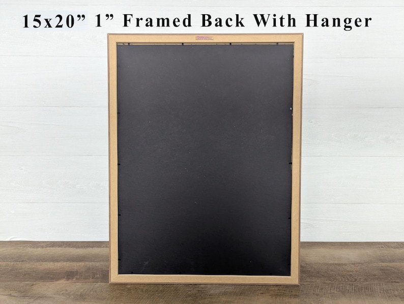 May include: A framed artwork's back, measuring 15x20 inches with a 1-inch frame, is displayed. The frame is a light brown color, and the back is black. The text "15x20" 1" Framed Back With Hanger" is visible at the top.