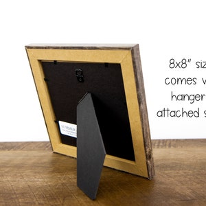 May include: A wooden picture frame with a rustic, weathered appearance. The frame is an 20x20 cm size and includes a hanger and attached stand for versatile display options. The frame has a neutral color palette.