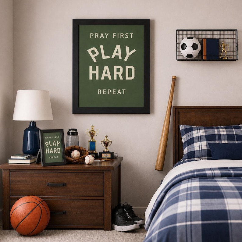 Black color frame of a Christian sports framed wall art with the phrase Pray First Play Hard Repeat on a green background in a vertical layout. Pictured in a boys room.