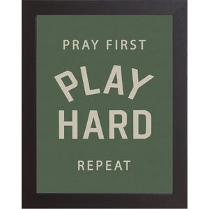 Black color frame of a Christian sports framed wall art with the phrase Pray First Play Hard Repeat on a green background in a vertical layout