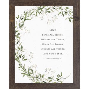 May include: Framed print with the text "LOVE BEARS ALL THINGS, BELIEVES ALL THINGS, HOPES ALL THINGS, ENDURES ALL THINGS. LOVE NEVER ENDS." surrounded by a green and white floral wreath. The frame is a dark brown color.