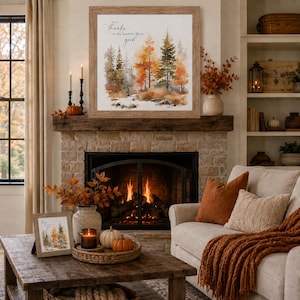 May include: A square wall art piece in a light wood frame featuring a watercolor forest scene with orange, yellow, and green trees and the text "Give thanks to the Lord for He is good" printed in black script at the top center of the white background.