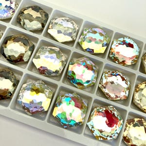 May include: A tray of iridescent, faceted, octagon-shaped rhinestones in various shades of blue, green, and purple.