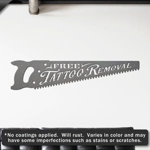 Sign shaped like a handsaw with the words Free Tattoo Removal cut out of it. The sign is raw steel.