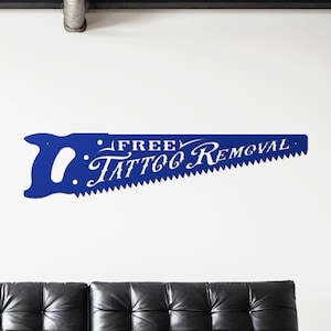 Sign shaped like a handsaw with the words Free Tattoo Removal cut out of it. Powder coated in a gloss blue powder coat.