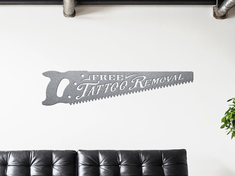 Sign shaped like a handsaw with the words Free Tattoo Removal cut out of it. Powder coated in a metallic silver powder coat.