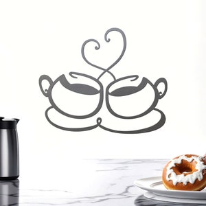 May include: A metal wall decor featuring two stylized coffee cups with a heart-shaped steam rising from them. The cups are in a black silhouette against a white background.