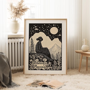 May include: Black and white illustration of a person sitting on a hilltop under a starry night sky with a full moon. The text "Dreaming is Planning" is below the person.