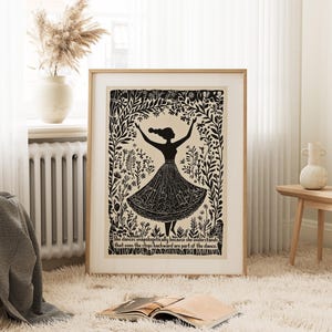 May include: A framed art print featuring a black silhouette of a dancing figure with arms raised. The figure is surrounded by floral and botanical elements. The print includes the text: "She dances unapologetically because she understands that even the steps backward are part of the dance."