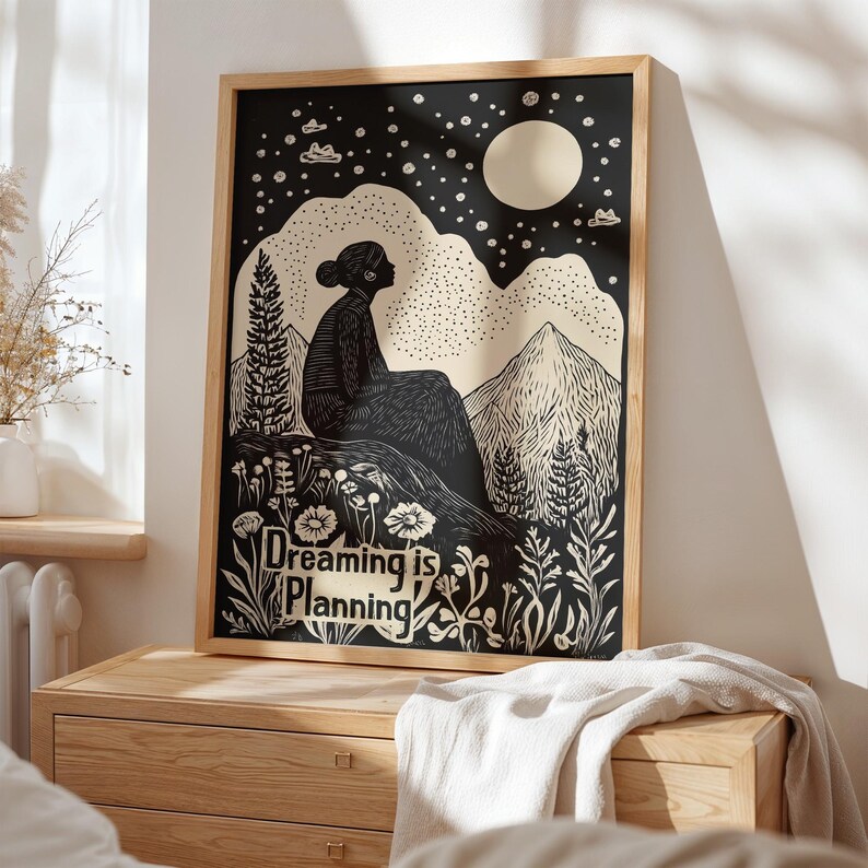 May include: Black and white illustration of a person sitting on a hilltop under a crescent moon and stars. The text "Dreaming is Planning" is below the person.