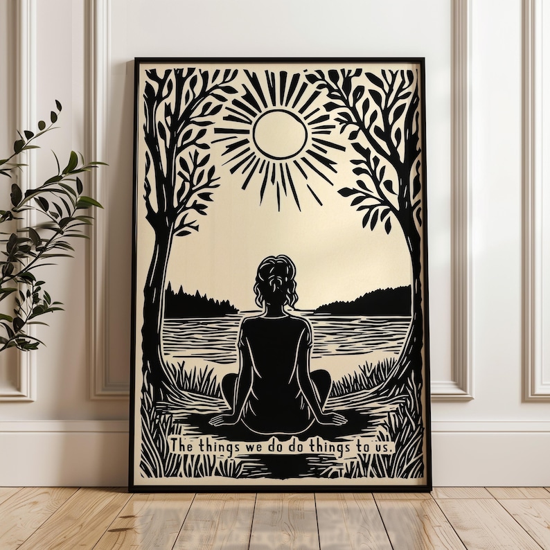 May include: Black and white framed art print featuring a silhouette of a person meditating by a lake, framed by trees and a sunburst. The text at the bottom reads, "The things we do do things to us."