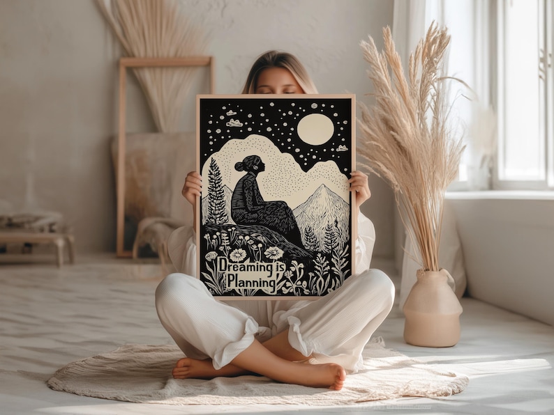 May include: Black and white illustration of a person sitting on a hill with a full moon and stars in the sky. The text "Dreaming is Planning" is at the bottom of the image.