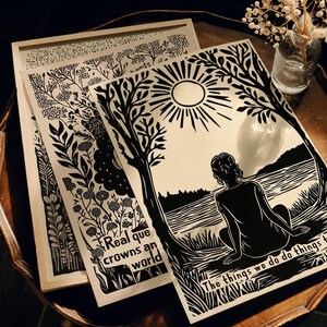 May include: Black and white art prints featuring nature-inspired designs and text. One print shows a figure by a lake with the text "The things we do do things to us." Another print has the text "Real que crowns an world."