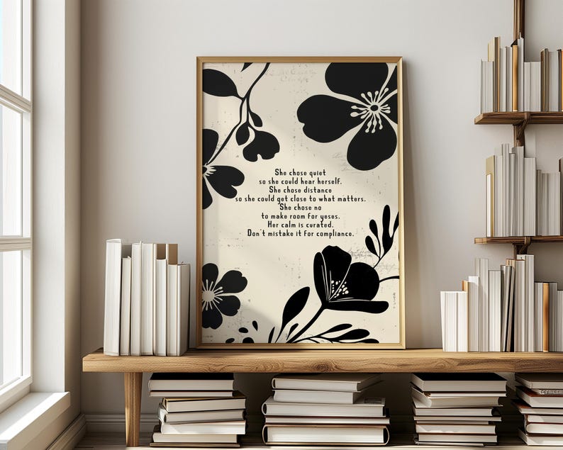 Puede incluir: Una impresi&oacute;n art&iacute;stica enmarcada con un borde dorado, que presenta dise&ntilde;os florales negros y texto inspirador. El texto dice: "She chose quiet...Don't mistake it for compliance". La impresi&oacute;n est&aacute; en un estante de madera con libros.