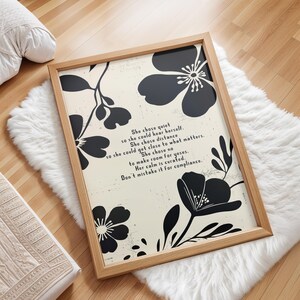 Puede incluir: Una impresi&oacute;n art&iacute;stica enmarcada con un marco de madera clara. La impresi&oacute;n presenta dise&ntilde;os florales negros y texto sobre un fondo blanquecino. El texto dice: "She chose quiet...Don't mistake it for compliance."