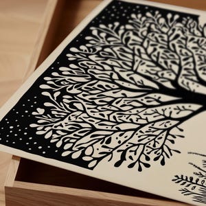 May include: A black and white art print featuring a stylized tree design. The artwork has a detailed, intricate pattern of branches and leaves against a cream-colored background. The print is displayed in a wooden box.
