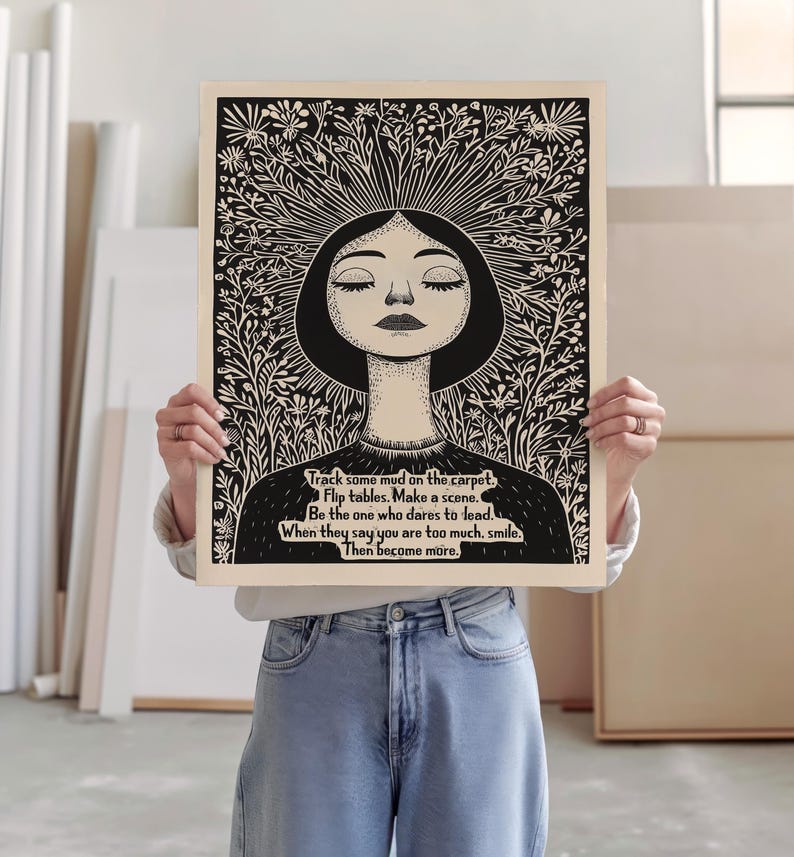 May include: Black and white illustration of a woman with her eyes closed, surrounded by flowers. The text reads: "Track some mud on the carpet. Flip tables. Make a scene. Be the one who dares to lead. When they say you are too much, smile. Then become more."
