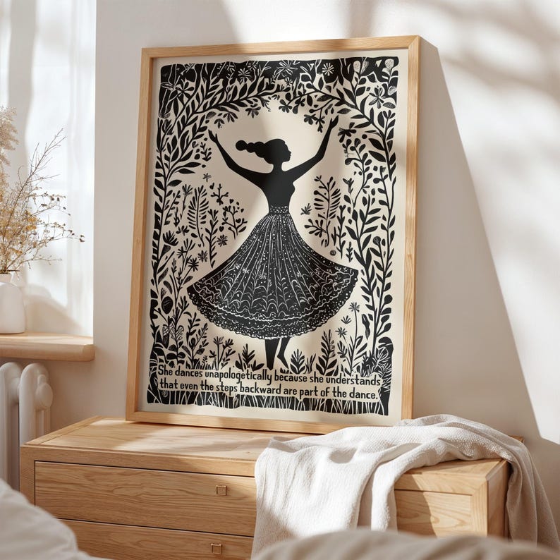 May include: Black and white framed art print featuring a silhouette of a dancing figure with arms raised. The figure is surrounded by floral and leaf designs. Text at the bottom reads: "She dances unapologetically because she understands that even the steps backward are part of the dance."