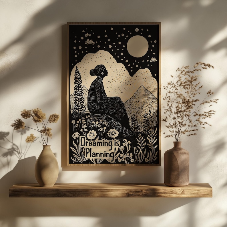 May include: Black and white illustration of a person sitting on a hilltop under a crescent moon and stars. The text "Dreaming is Planning" is below the person.