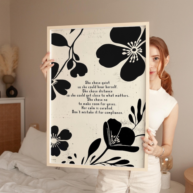 Puede incluir: Un cuadro enmarcado con dise&ntilde;os florales negros sobre un fondo crema. La impresi&oacute;n incluye el texto: "She chose quiet...Don't mistake it for compliance." El marco es de color madera clara.