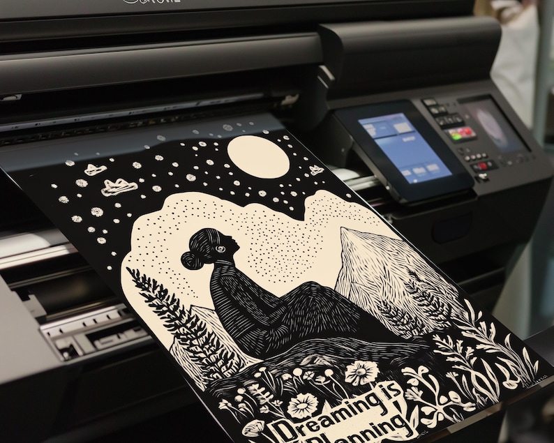 May include: Black and white illustration of a person sitting on a mountain with a moon and stars in the background. The text "Dreaming is  planning" is at the bottom of the image.