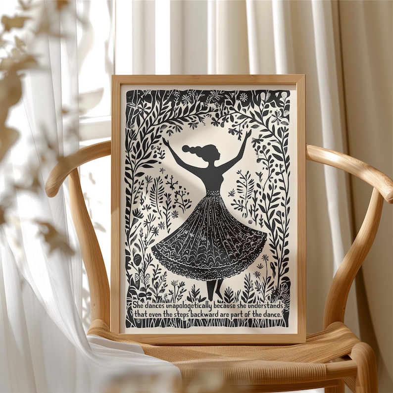 May include: A framed black and white art print featuring a silhouette of a dancing figure with arms raised. The figure is surrounded by floral and botanical elements. The print includes the quote: "She dances unapologetically because she understands that even the steps backward are part of the dance."