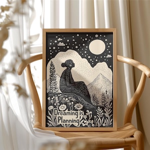 May include: Black and white illustration of a person sitting on a hill under a starry night sky with a full moon. The text "Dreaming is Planning" is at the bottom of the image.