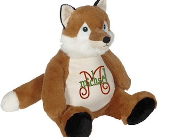 May include: A brown and white plush fox with black paws and a white belly. The fox is sitting with its legs outstretched and has a white patch on its tail. The fox has a green and orange embroidered letter "M" on its chest with the name "Michael" written below it.
