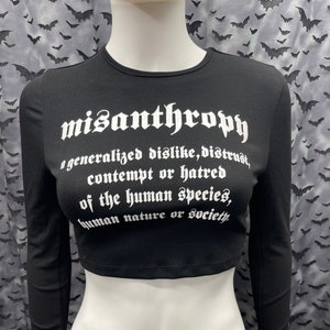 May include: Black long-sleeved crop top with white text that reads "misanthropy a generalized dislike, distrust, contempt or hatred of the human species, human nature or society."
