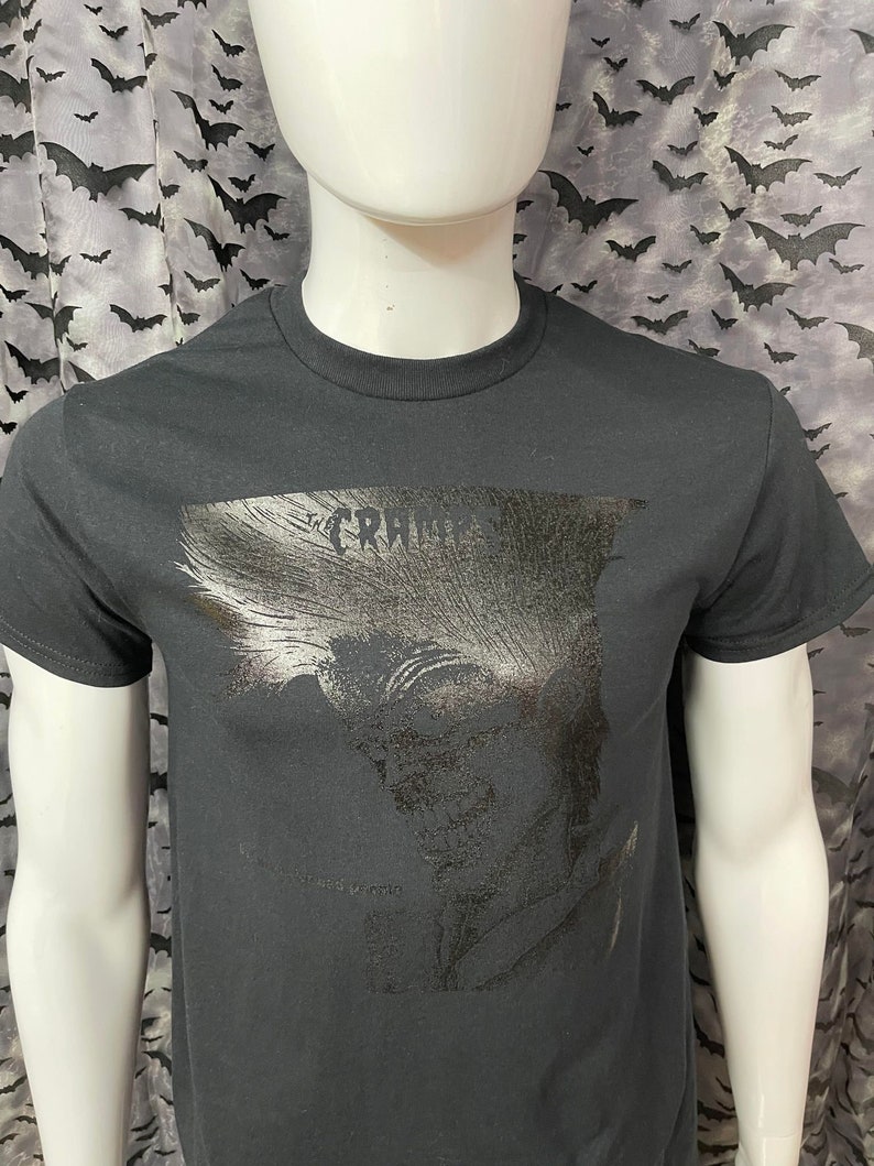 May include: Black t-shirt with a silver graphic print of a skull with the text "The Cramps" above it.