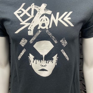 May include: Black t-shirt with a white graphic print of a stylized face with dripping makeup and the word "EXISTENCE" above it.