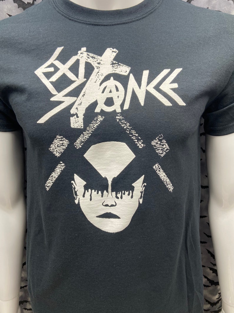 May include: Black t-shirt with a white graphic print of a stylized face with dripping makeup and the word "EXISTENCE" above it.