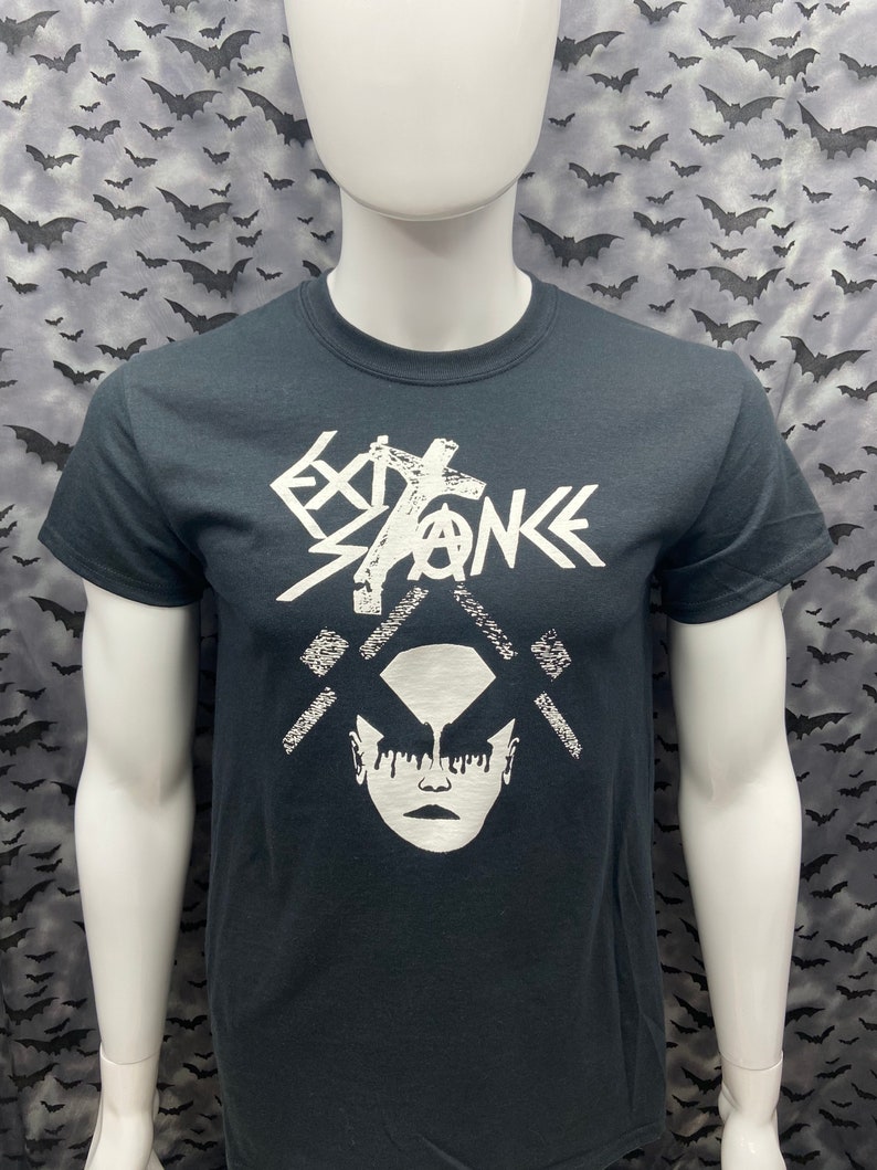 May include: Black t-shirt with a white graphic design. The design features a stylized face with dripping makeup and the text "EXTINCTION" with an anarchy symbol.