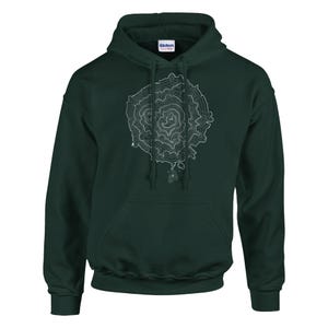 Può includere: Felpa con cappuccio verde scuro con un design a mappa topografica bianca. La mappa presenta cerchi e linee concentriche, creando un motivo astratto dettagliato. La felpa ha una tasca frontale e un cappuccio con coulisse.