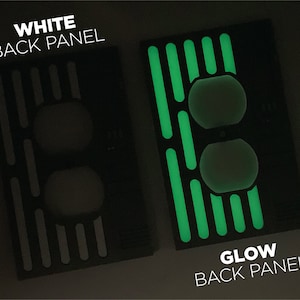 Puede incluir: Dos placas traseras para un interruptor de luz. La placa de la izquierda es blanca y la placa de la derecha es negra con l&iacute;neas verdes que brillan en la oscuridad. El texto "WHITE BACK PANEL" est&aacute; encima de la placa de la izquierda y "GLOW BACK PANEL" est&aacute; debajo de la placa de la derecha.