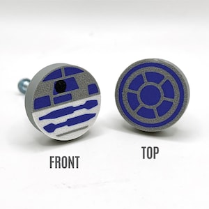 May include: A round, gray and blue knob with a design of the character R2-D2 from Star Wars. The knob is shown from the front and top.