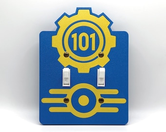 May include: Blue wall plate with a yellow gear and the number 101. Two white light switches are below the gear. The bottom of the plate has a yellow design with a circle in the middle. The switches are in the "ON" position.