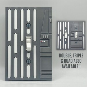 May include: A gray light switch cover plate featuring a vertical pattern of white rectangular slots and a central white toggle switch. The design includes a rectangular control panel detail on the right side. Text on the right reads: DOUBLE, TRIPLE & QUAD ALSO AVAILABLE!!
