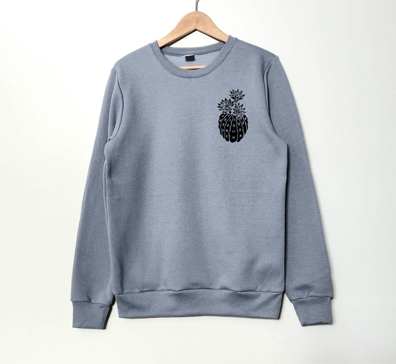 May include: A gray sweatshirt with a black graphic of a pineapple on the left chest.